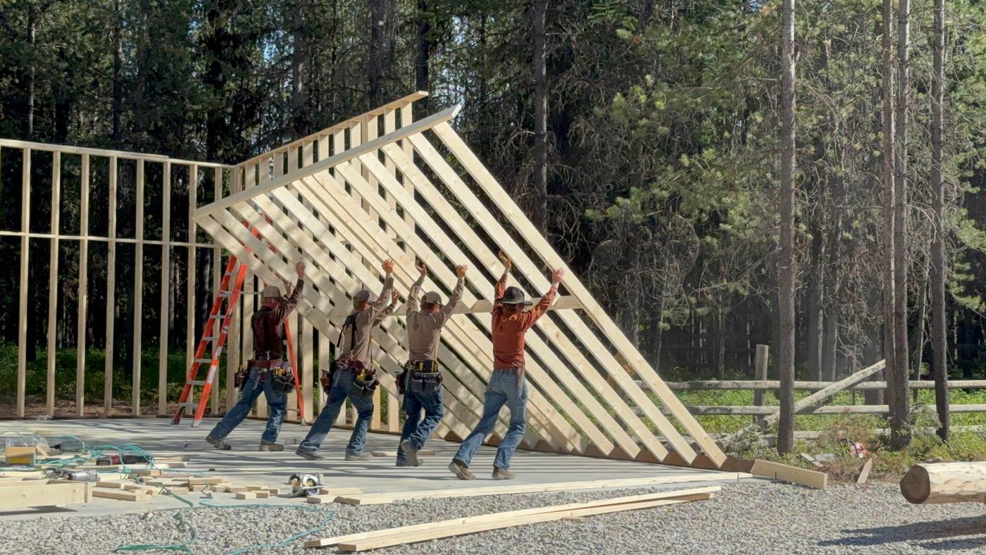 Four of the crew raising a framed wall by hand