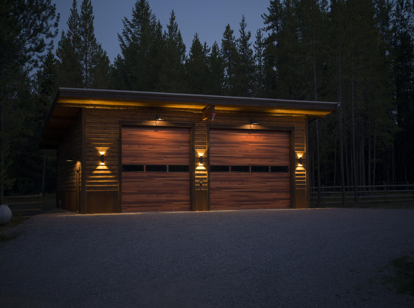 The garage at dusk with the exterior lights on and the doors lit