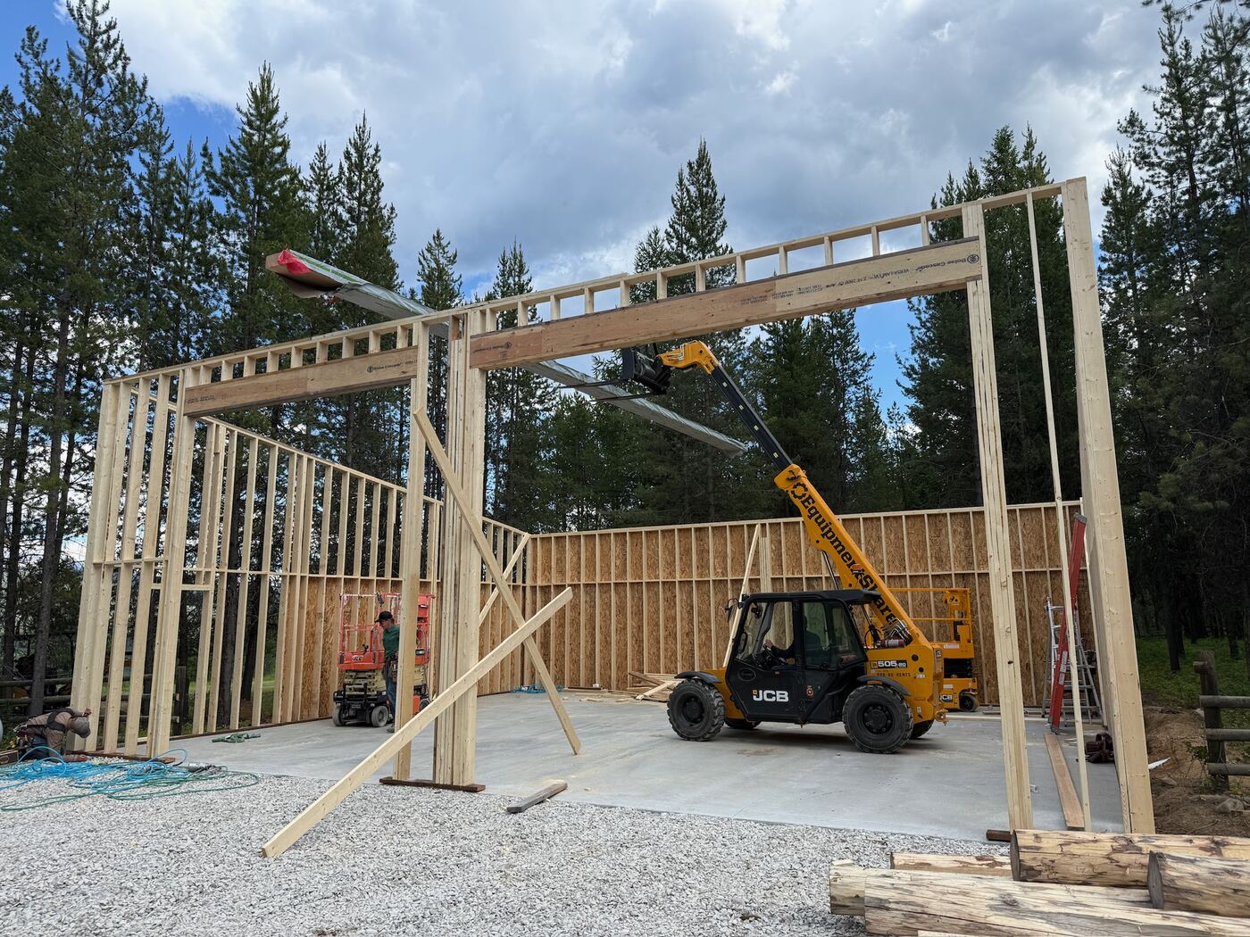 A telehandler setting a long beam across the open bays of the frame
