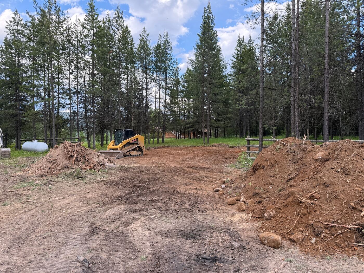 A track loader shaping the graded building area with spoil piled either side